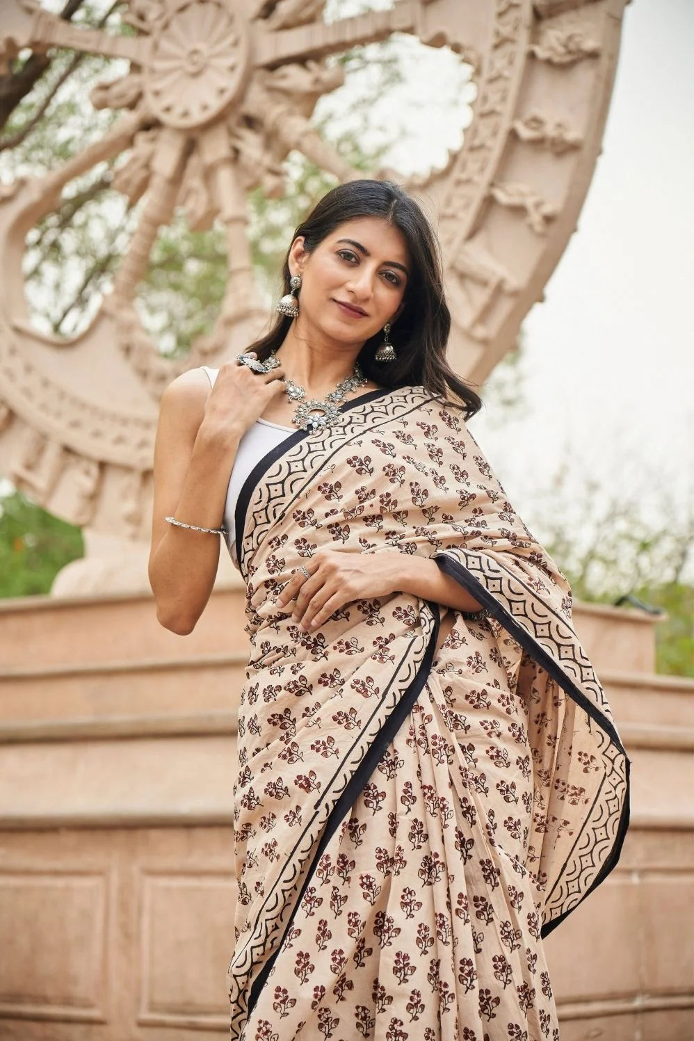 Cream red mulmul cotton saree with artistic block printing.