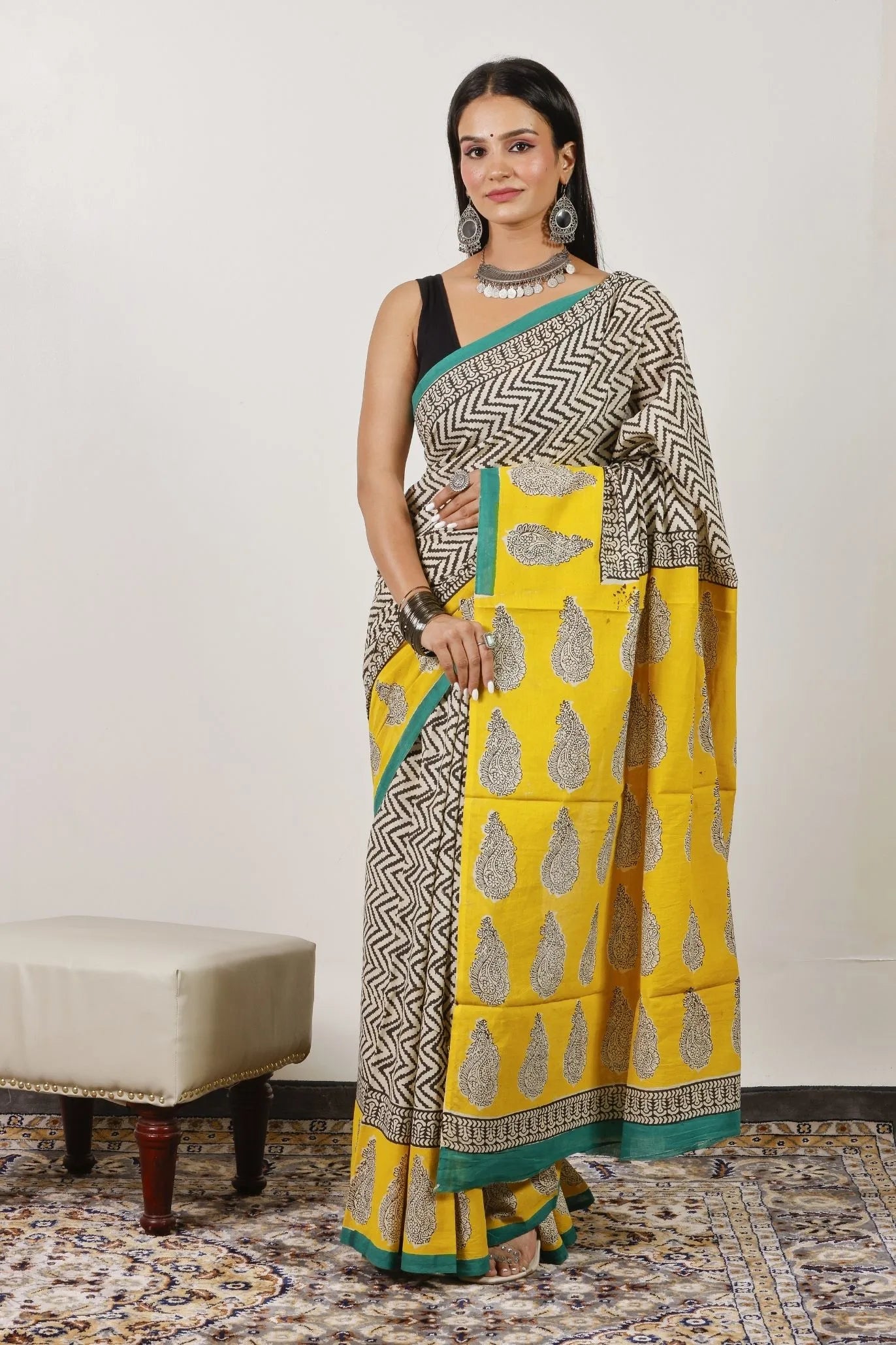Woman wearing a yellow saree with a patterned border against a white background