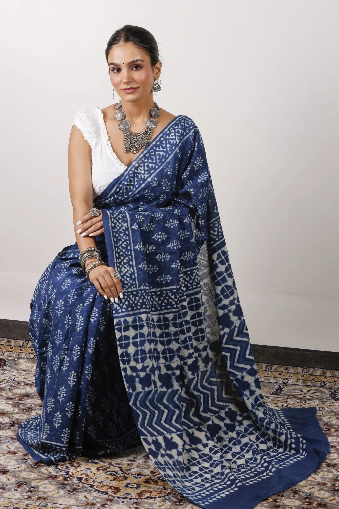 Woman wearing a blue saree with a white blouse.