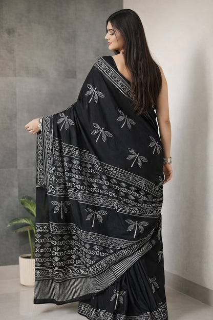 Woman wearing a black saree with white patterns in an indoor setting
