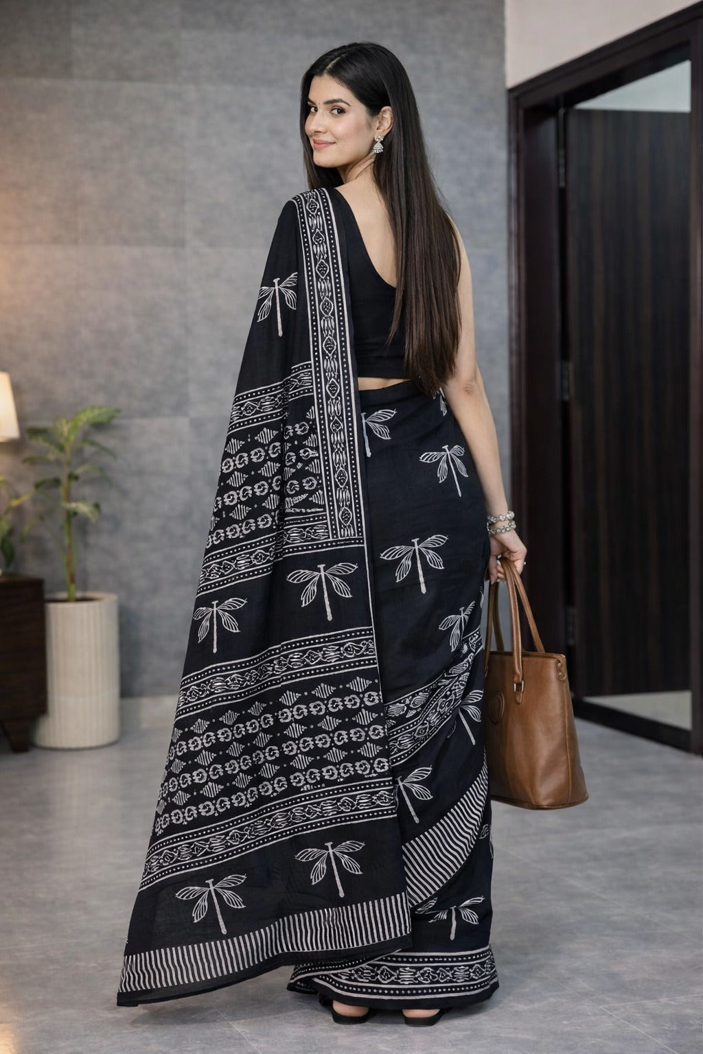 Woman wearing a black saree with white patterns in an indoor setting