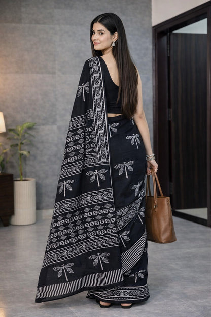 Woman wearing a black saree with white patterns in an indoor setting