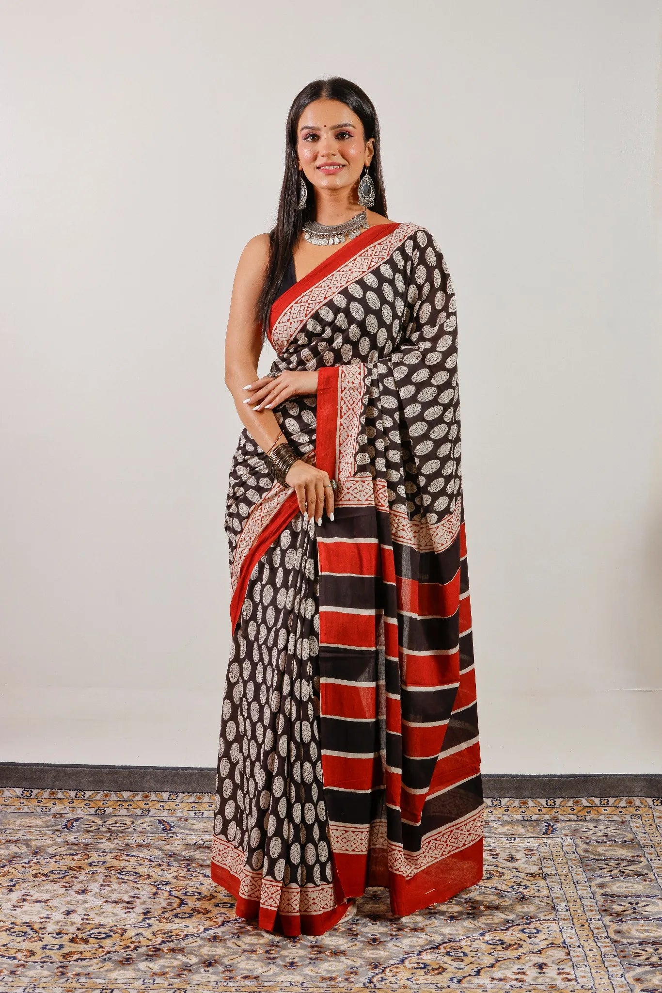 Black hand block print mulmul cotton saree with red border and striped pallu – full front view.