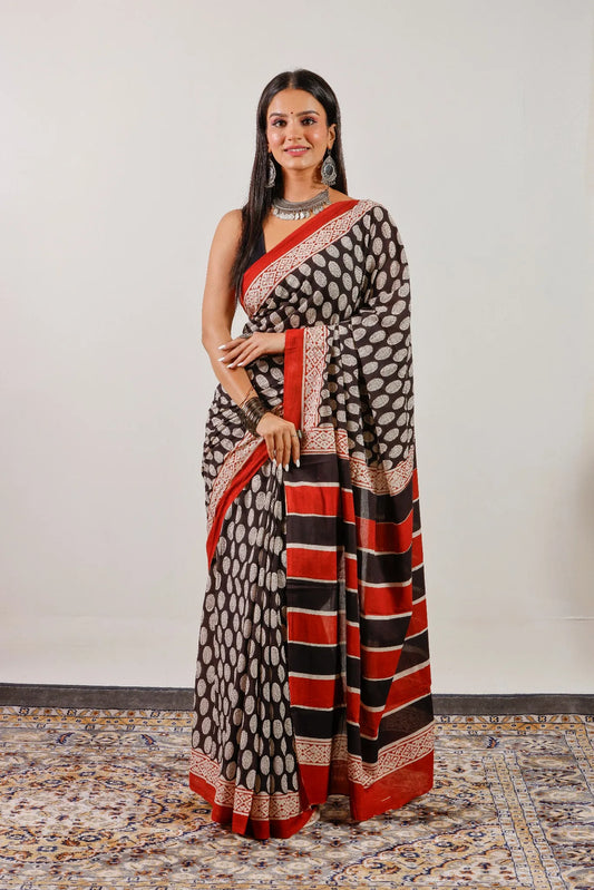 Black hand block print mulmul cotton saree with red border and striped pallu – full front view.