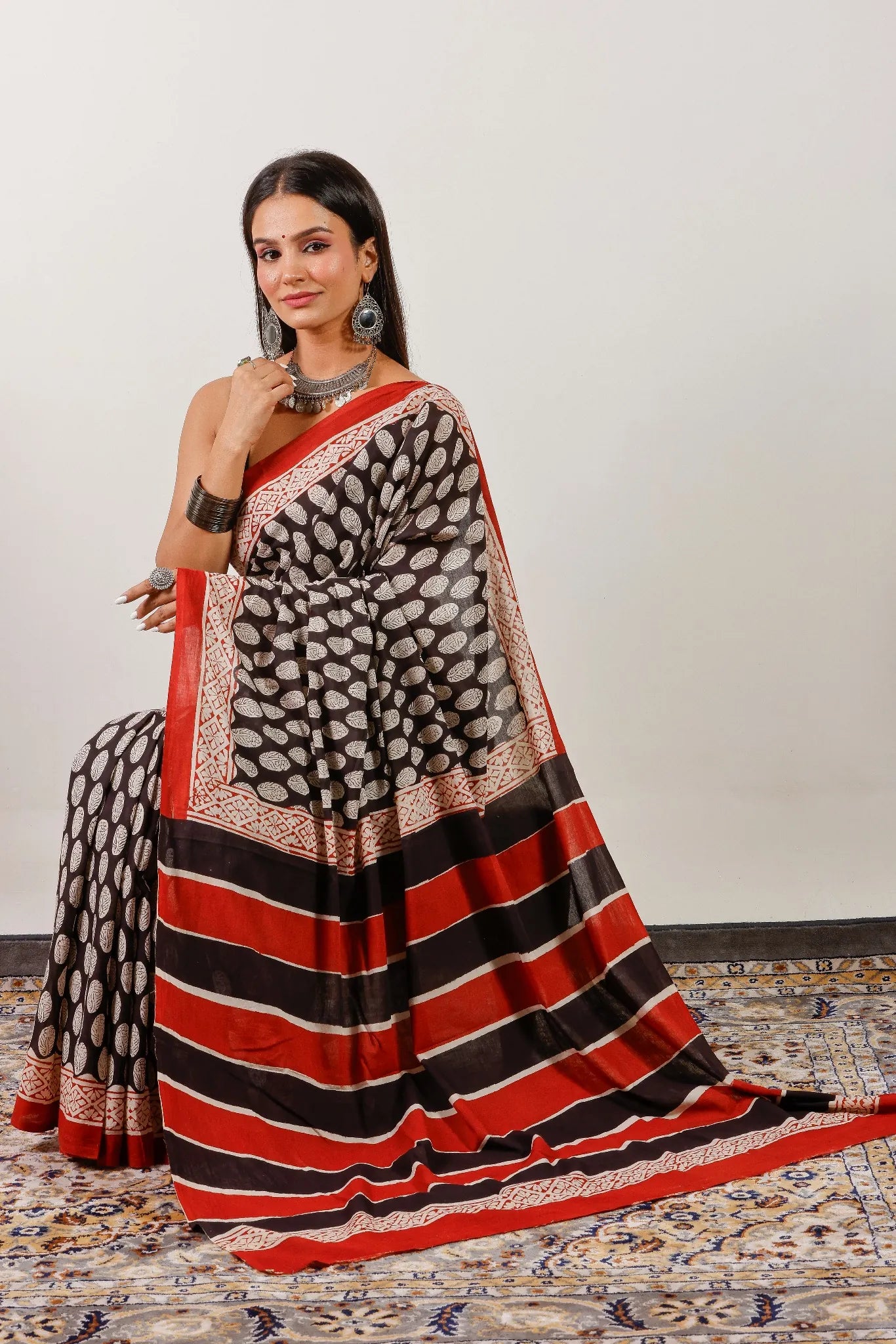 Women's black cotton saree with red striped pallu and traditional Indian block print design.